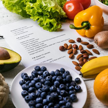 Assortment of fruits, nuts, and vegetables next to a recipe