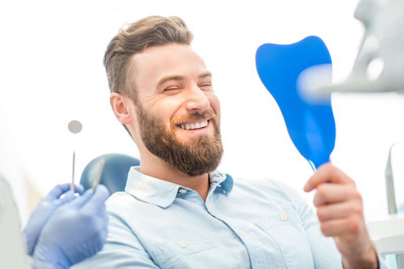 a patient checking his smile with a mirror